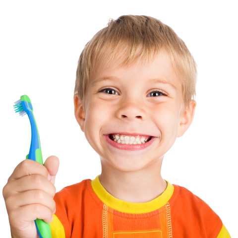 A cheerful young boy with blonde hair, wearing an orange shirt, smiles widely while holding a green and blue toothbrush.